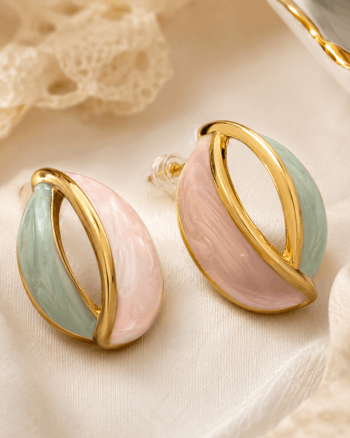 Pastel Orbit gold-tone hoop earrings with pink and mint enamel photographed on ivory satin