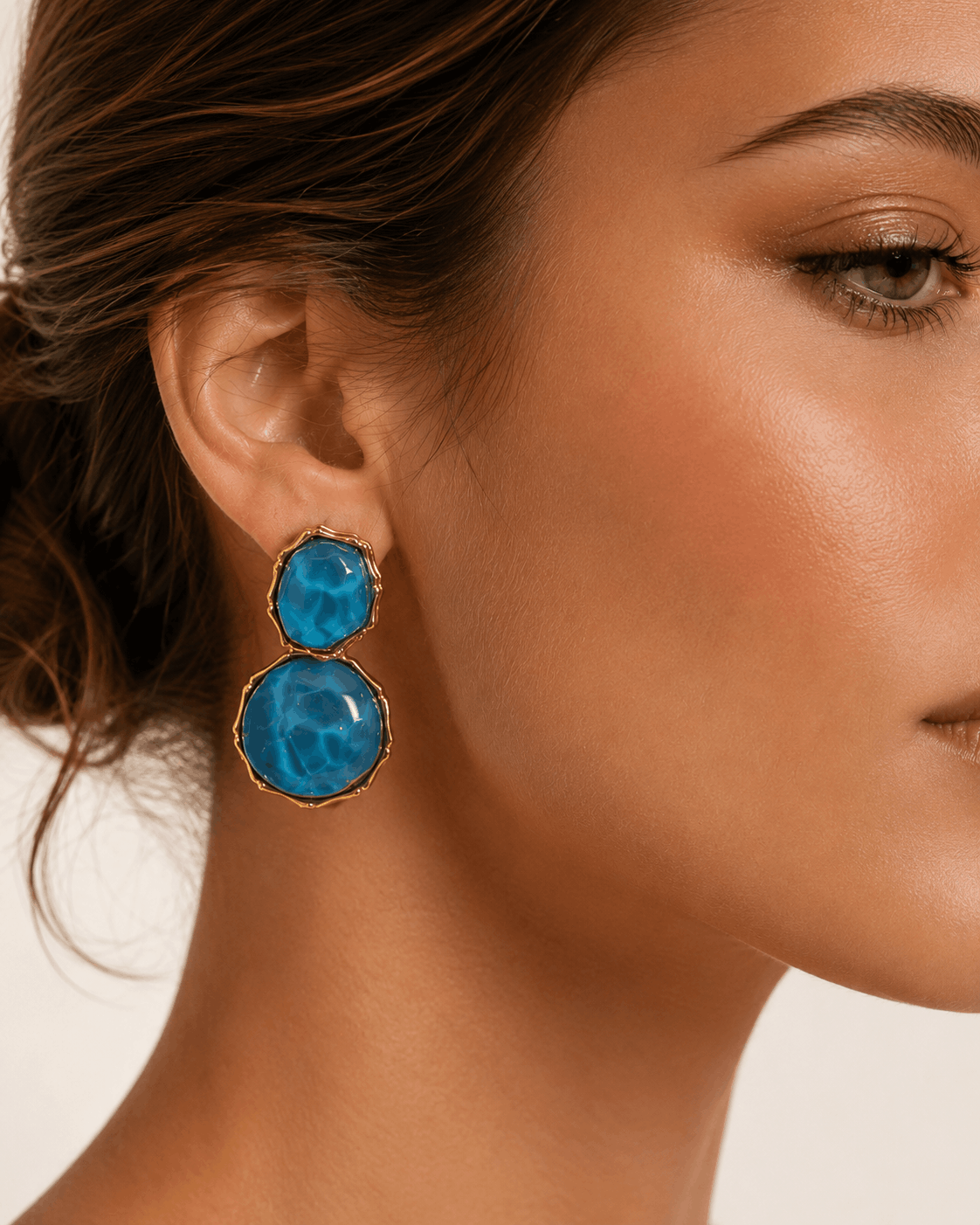 Azure Muse gold-tone earrings with blue resin stones worn by a model