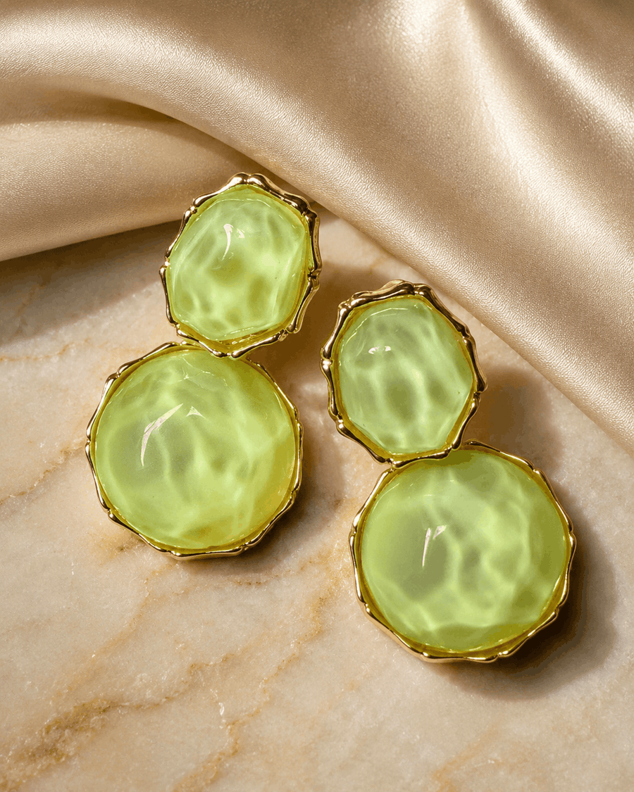 Verdant Muse gold-tone earrings with green resin stones photographed on marble