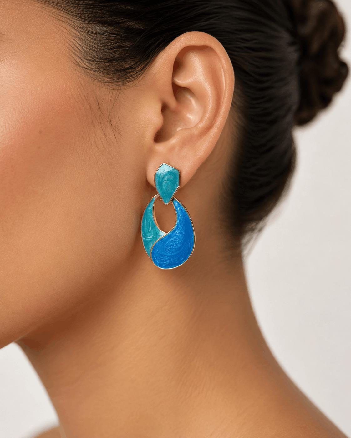 Ocean Muse gold-tone statement earrings with blue and teal enamel worn by a model