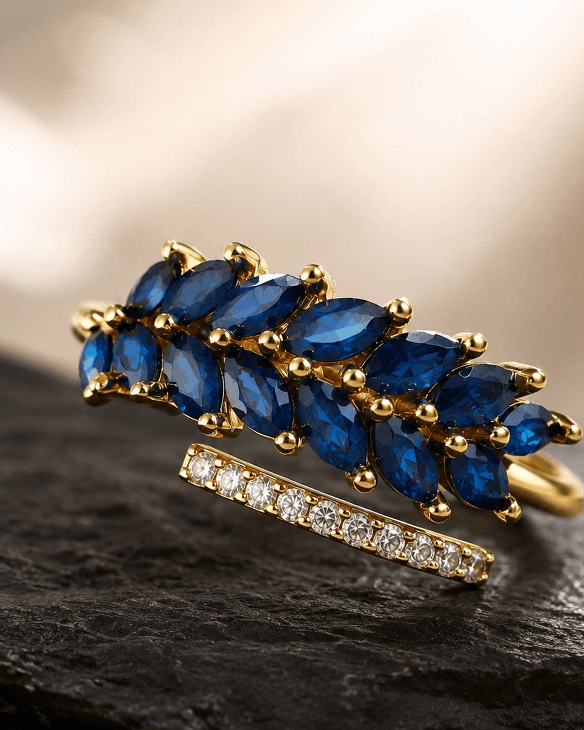 Midnight Aura gold-tone ring with blue marquise cubic zirconia photographed on a natural stone surface