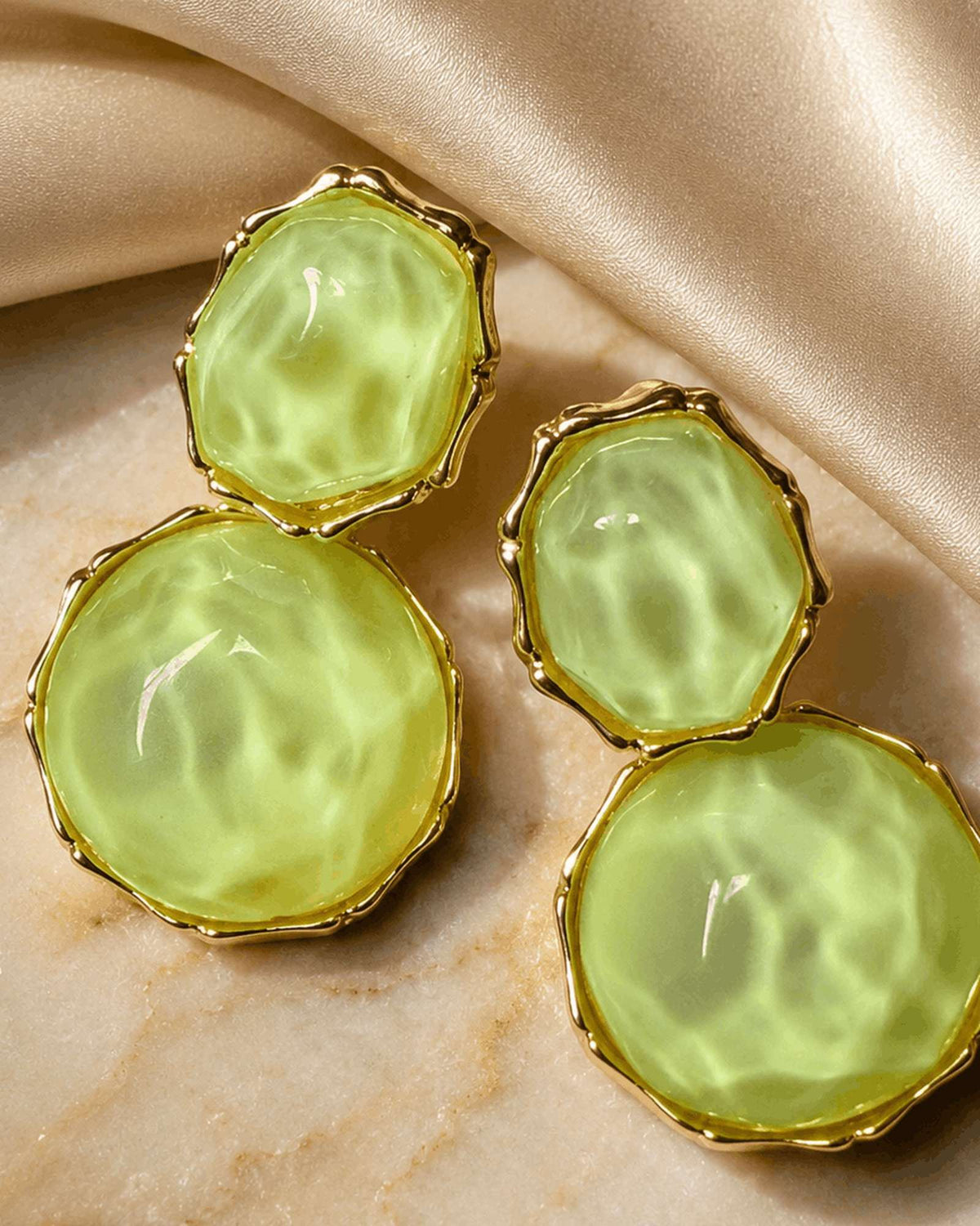 Verdant Muse gold-tone earrings with green resin stones photographed on marble
